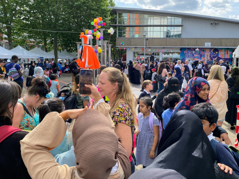 A large crowd of people attending the Well One Summer of Wellbeing Festival in Chrisp Street, Poplar