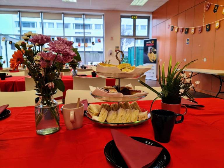 A pretty Just Say Hello high tea table setting with a selection of sandwiches and cakes