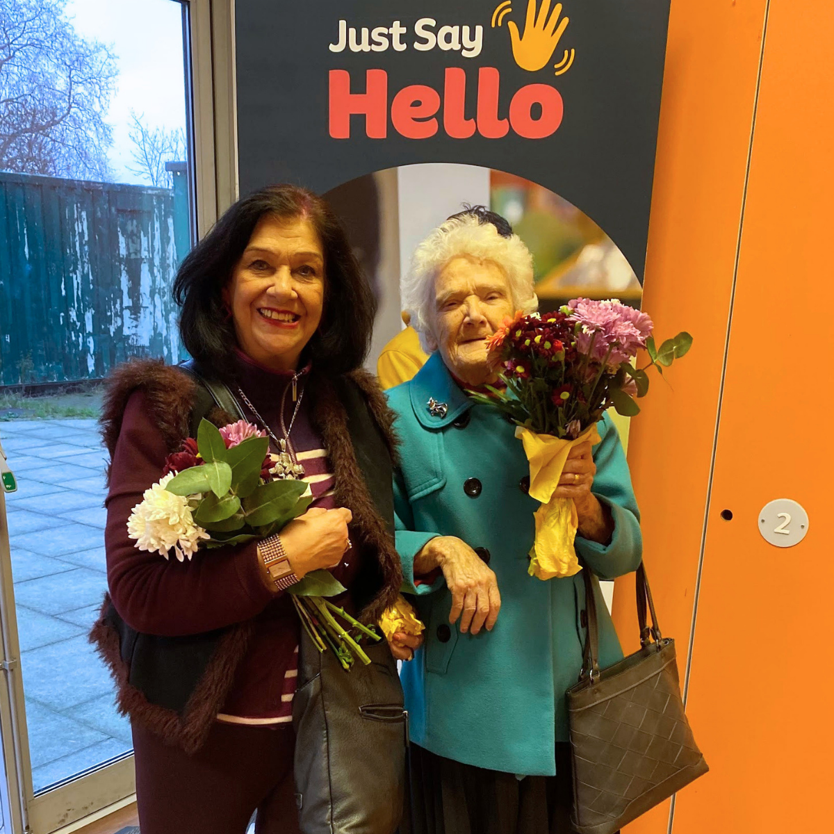 Two smiling neighbours from Bow meet up at a high tea community event at the Bernie Cameron Centre