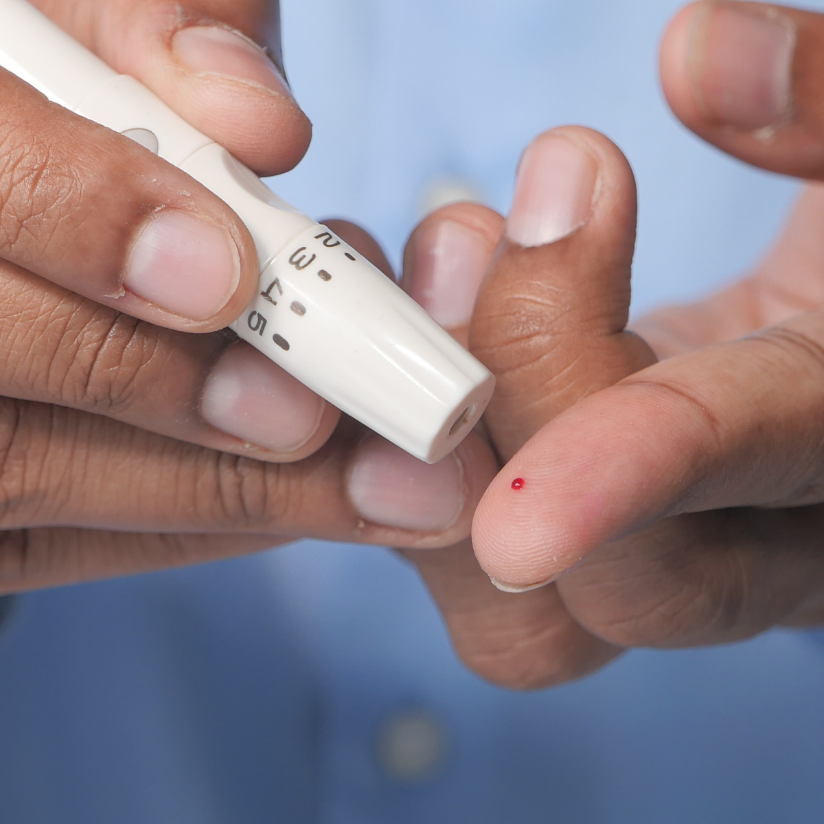 A man uses a lancet pen to draw a drop of blood and test his blood sugar level