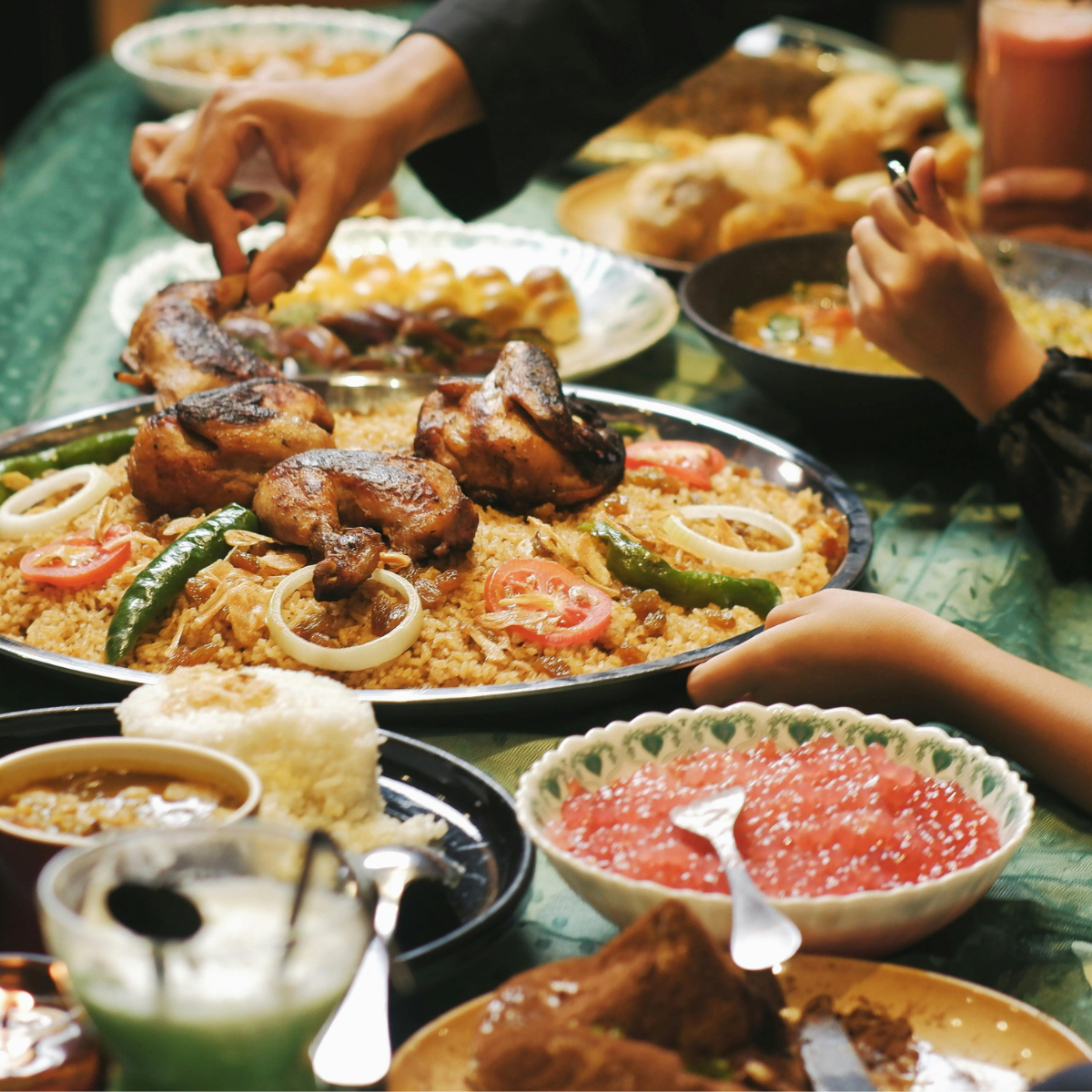 People's hands reach in to take food onto their plates during Iftar