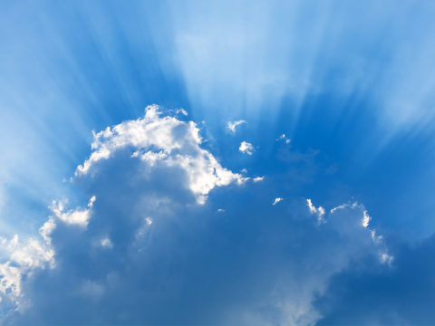 A photo of the sky with sunrays behind clouds