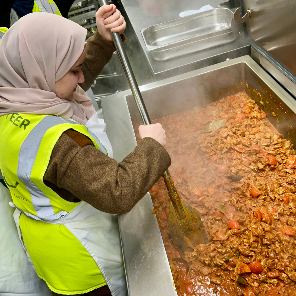 Nutritionist Shaymaa stirring the giant pot of her lamb curry recipe at the Felix Project kitchen