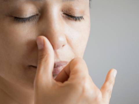 A woman is closing her eyes and practising a mindful breathing exercise