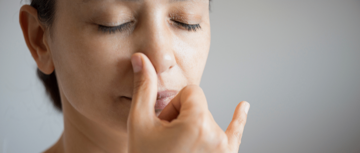 A woman is closing her eyes and practising a mindful breathing exercise