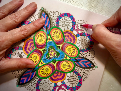 Person relaxing by colouring a mandala pattern