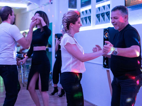 Men and women dancing salsa together in a community centre class