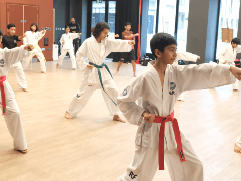 A group of young boys and girls practising punching techniques together during a Taekwondo class at Feldy Community Space
