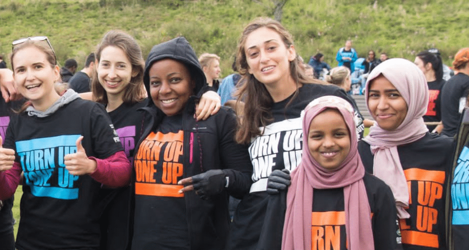 A group of people outside in the park, smiling and wearing Our Parks branded tshirts.