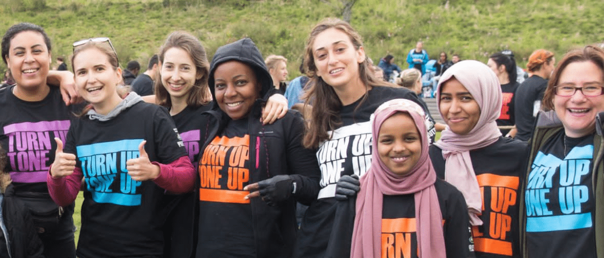 A group of people outside in the park, smiling and wearing Our Parks branded tshirts.