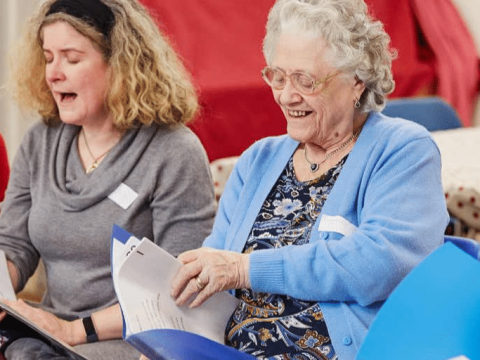 A group of older people are happily singing together