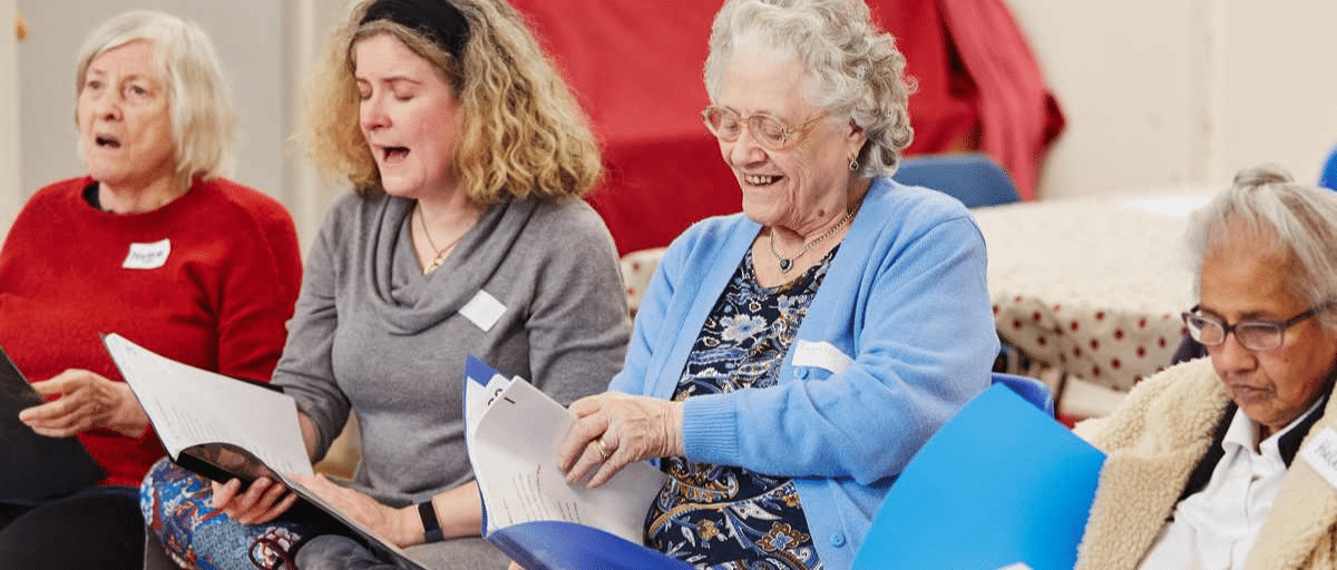 A group of older people are happily singing together