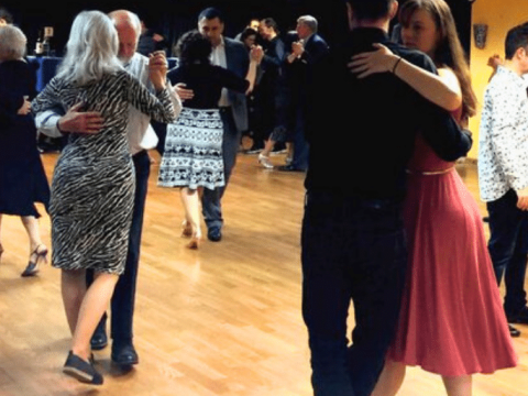 A group of people learning to dance tango in pairs