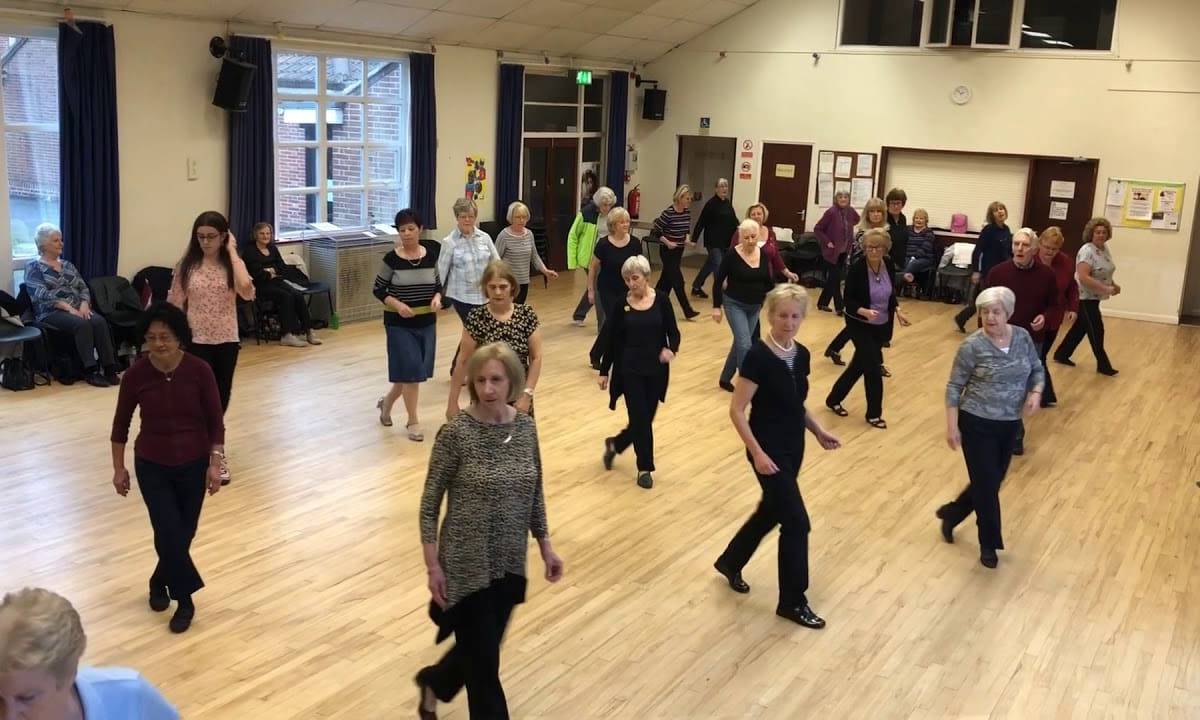 A group of people are line dancing in formation at the Linc Centre