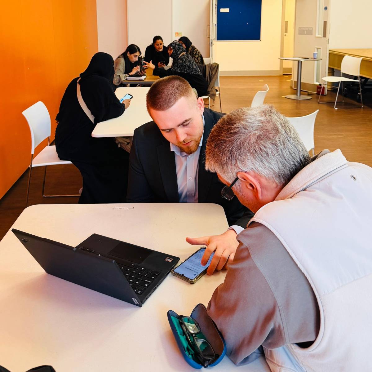 Local people being shown by volunteers how to use the NHS App on their mobile phones as part of the Tap Into Health project