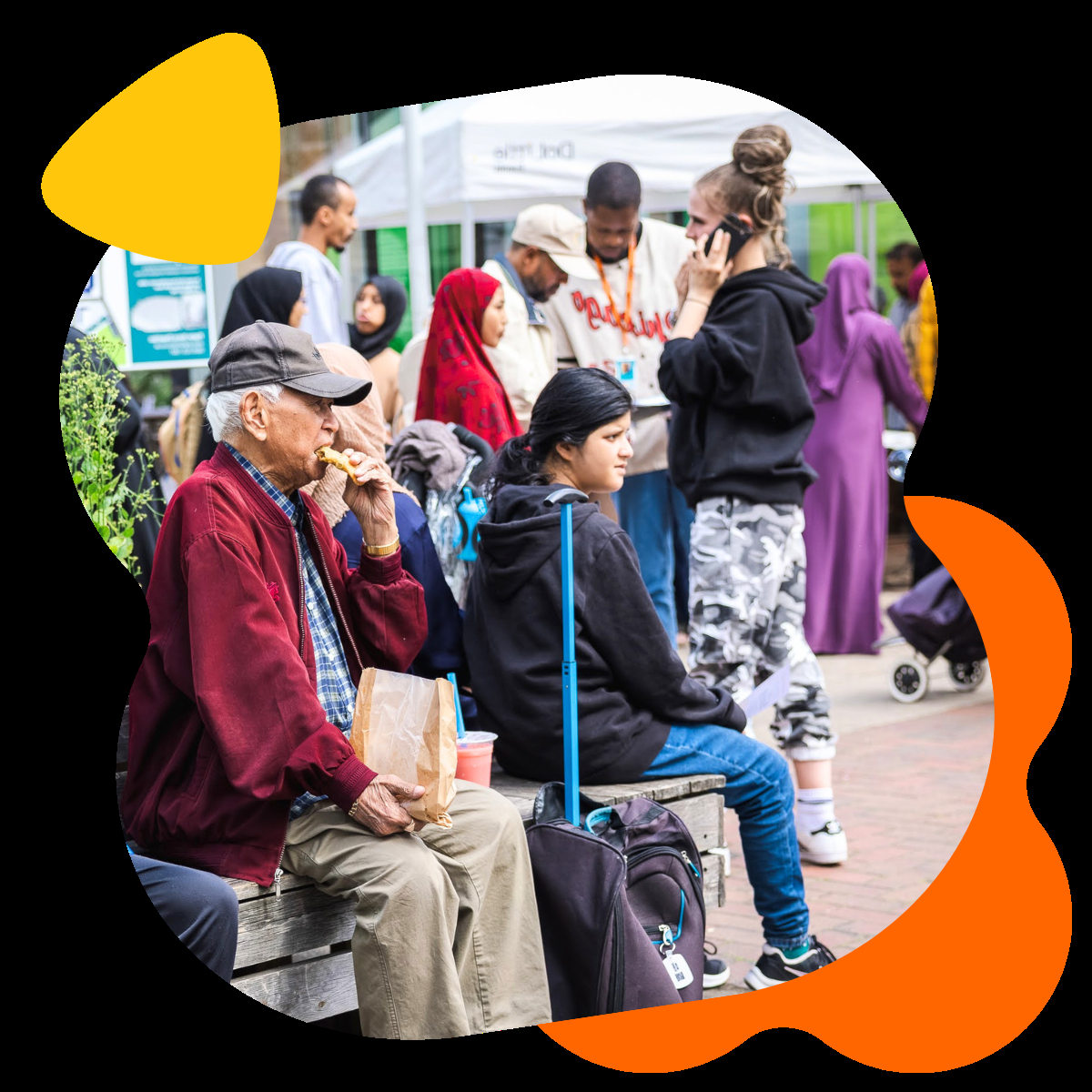 A group of people sitting and standing around the benches at Chrisp Street market, E14